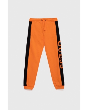 Guess spodnie dresowe bawełniane dziecięce kolor pomarańczowy z aplikacją
